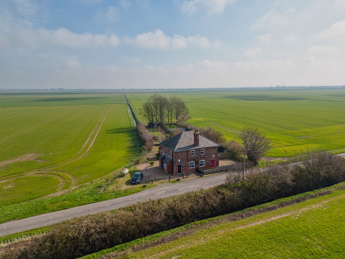 Aerial drone photograph of a rural cottage surrounded by open fields